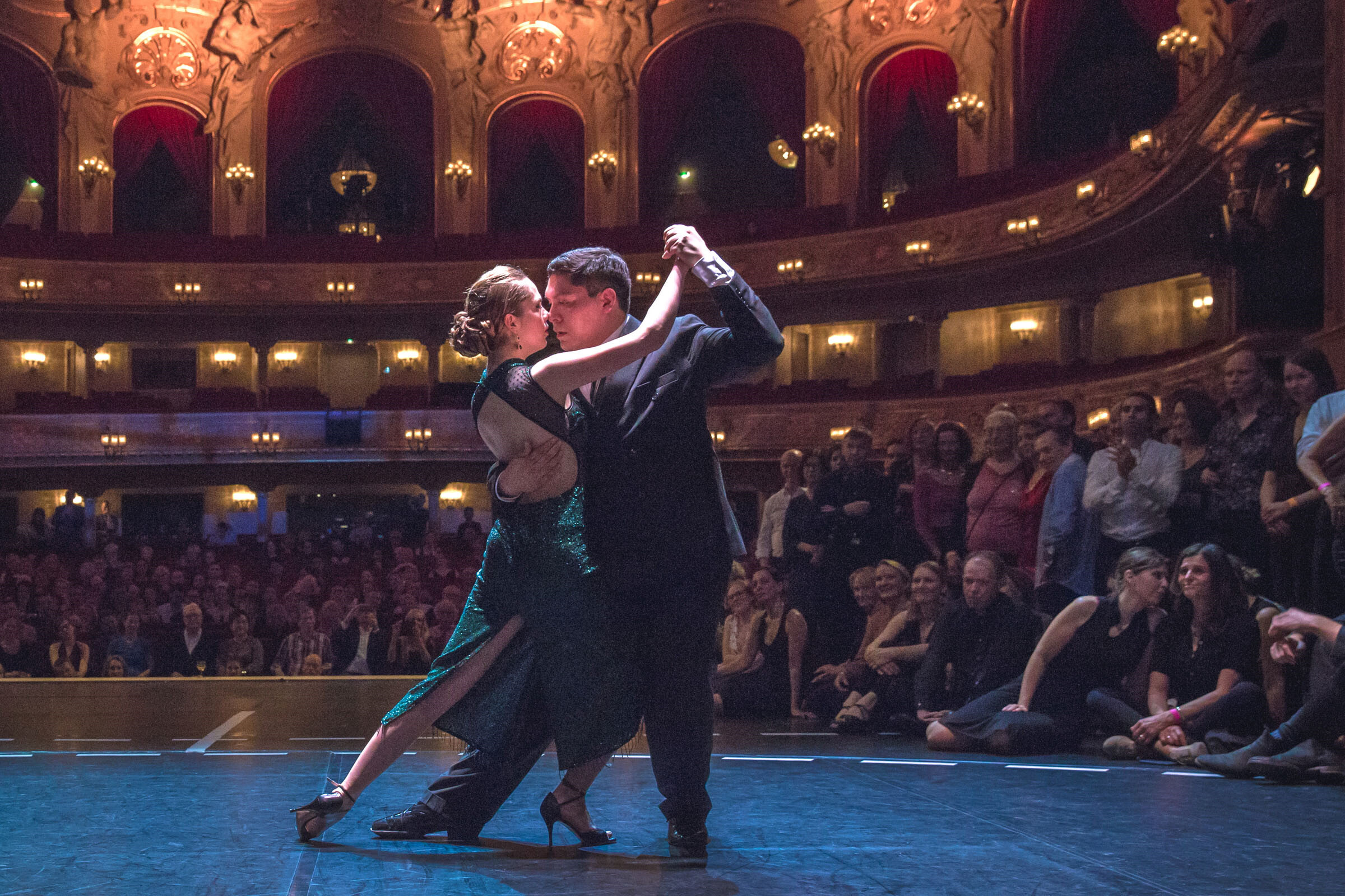 Ein Paar tanzt Tango auf der Bühne der Komischen Oper Berlin, im Hintergrund Zuschauer